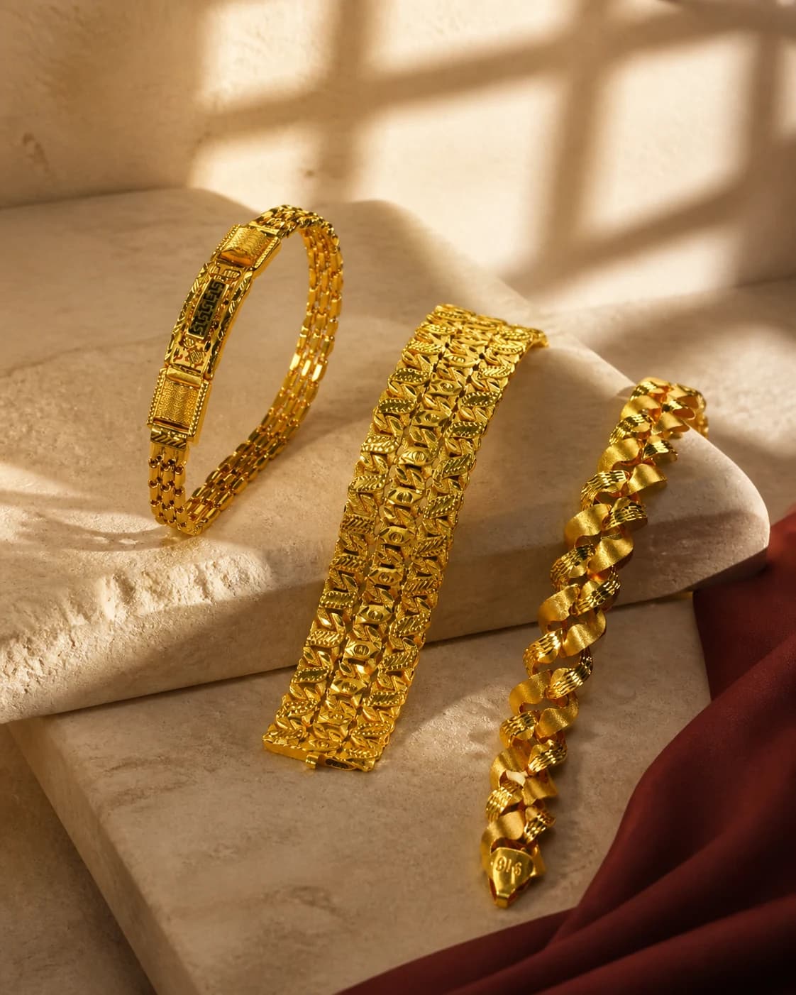 Three distinct handcrafted gold bangles arranged on warm ivory stone