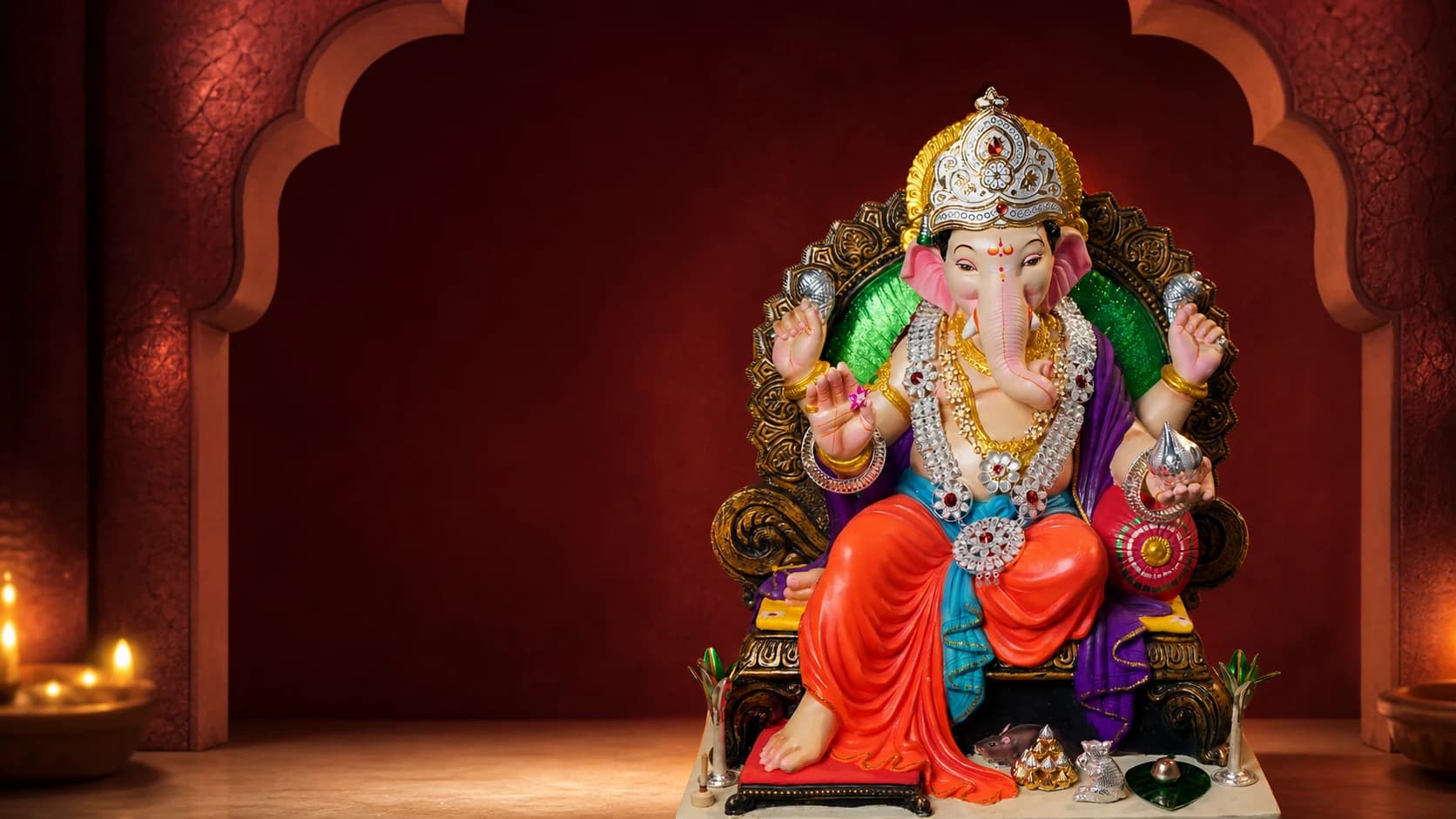 Ganpati idol adorned with gold and silver devotional jewellery in a wine-red alcove