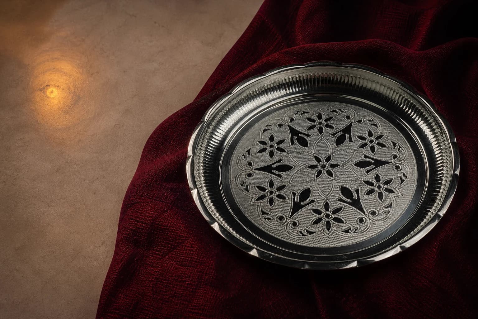 Engraved silver puja thali arranged on deep-maroon handloom cloth