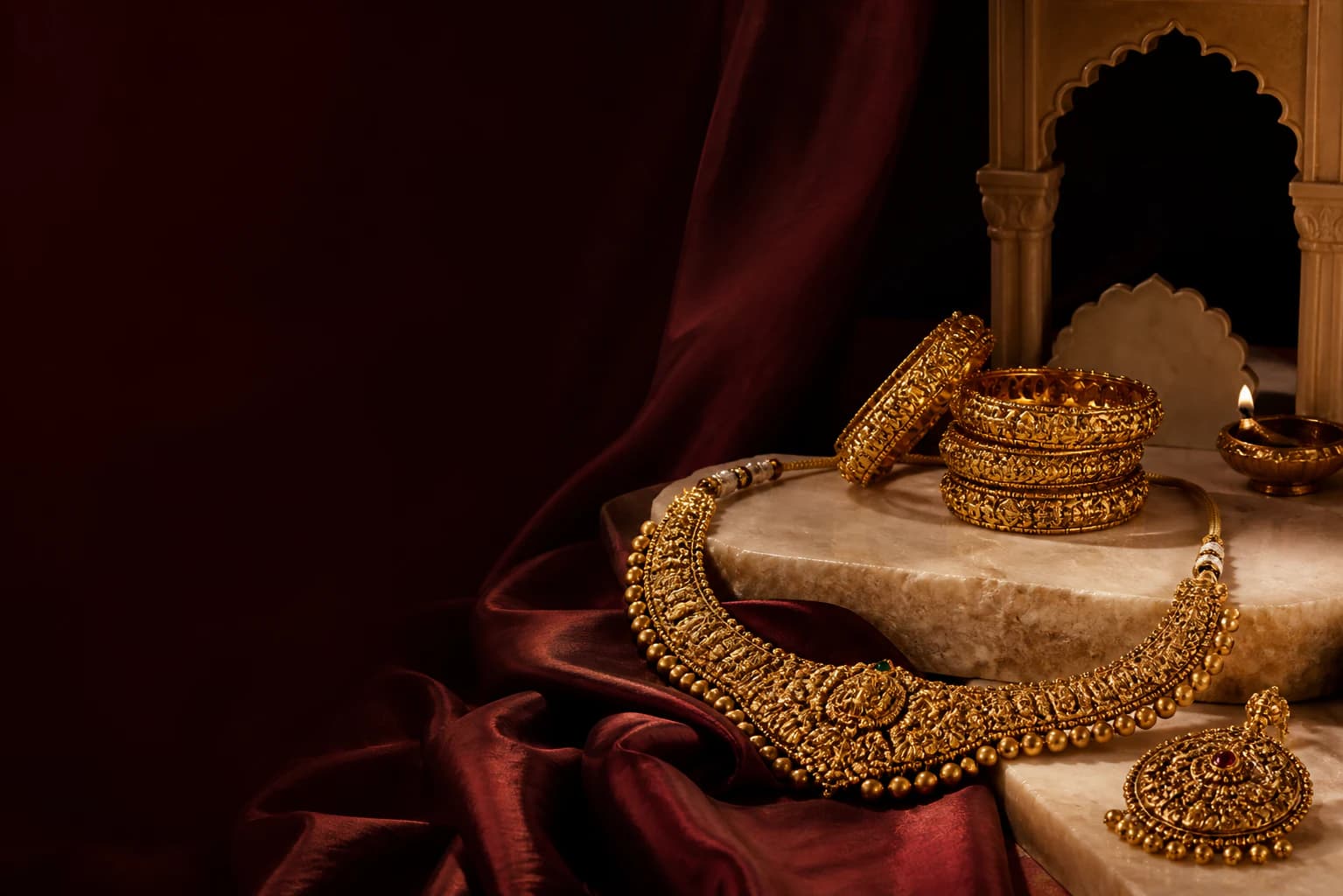 Maharashtrian gold jewellery arranged on oxblood silk and warm ivory stone