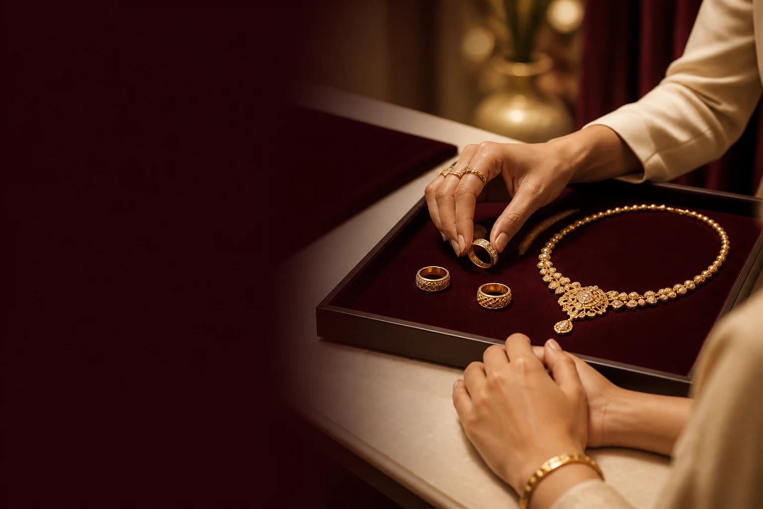 Private jewellery consultation with gold pieces presented on deep-maroon velvet